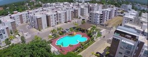 A residential area with modern apartment buildings, a central swimming pool, and surrounding greenery. - HeimatDorado R.D. your pleasant stay (Santiago de los Caballeros)