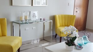 A modern living room with a glass coffee table, two yellow armchairs, a white cabinet, and a door. - HeimatDorado R.D. your pleasant stay (Santiago de los Caballeros)