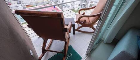 A balcony with two wooden chairs and a green doormat with "BIENVENIDO" text.