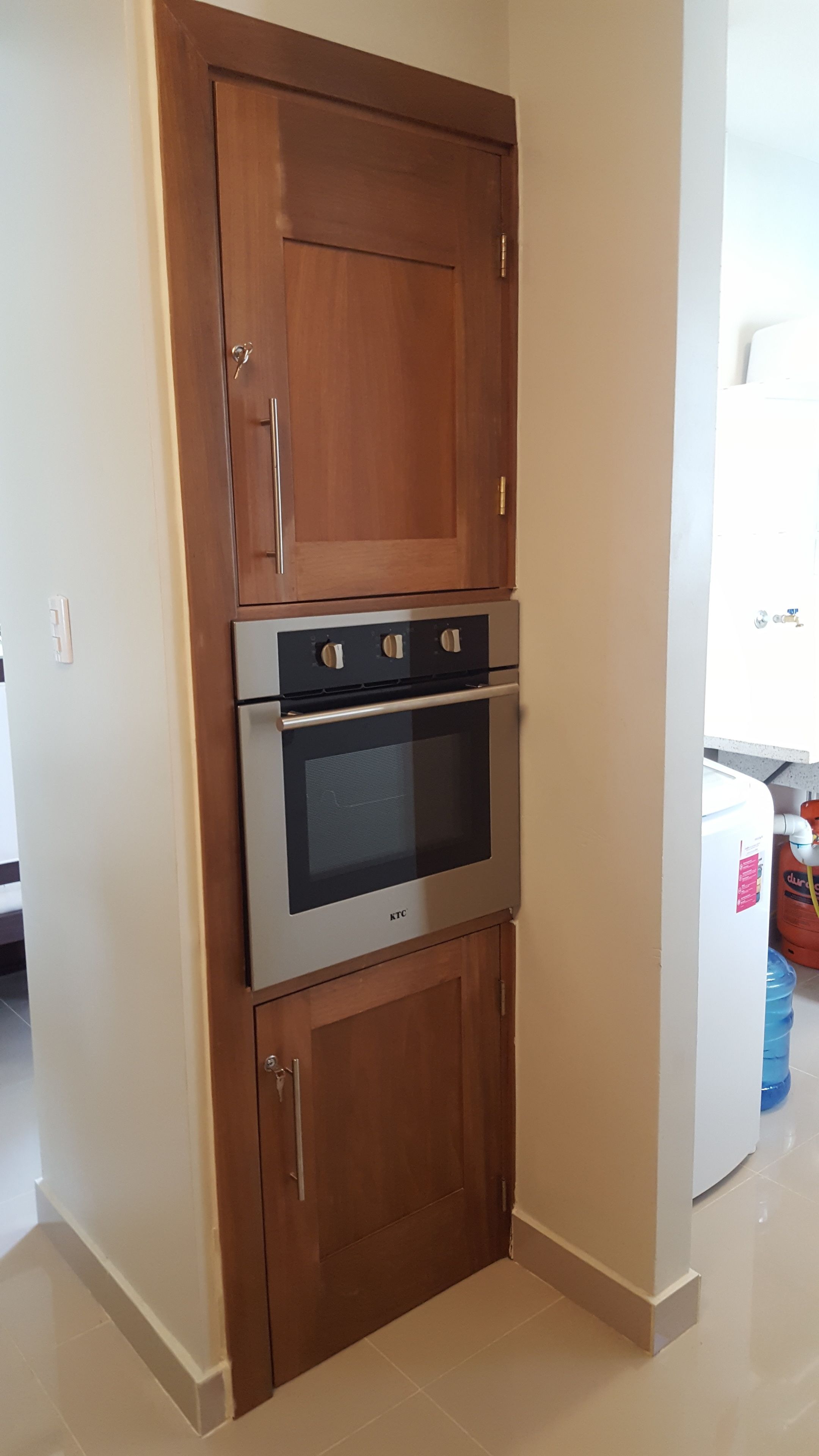 A kitchen with a built-in oven and a lower cabinet.