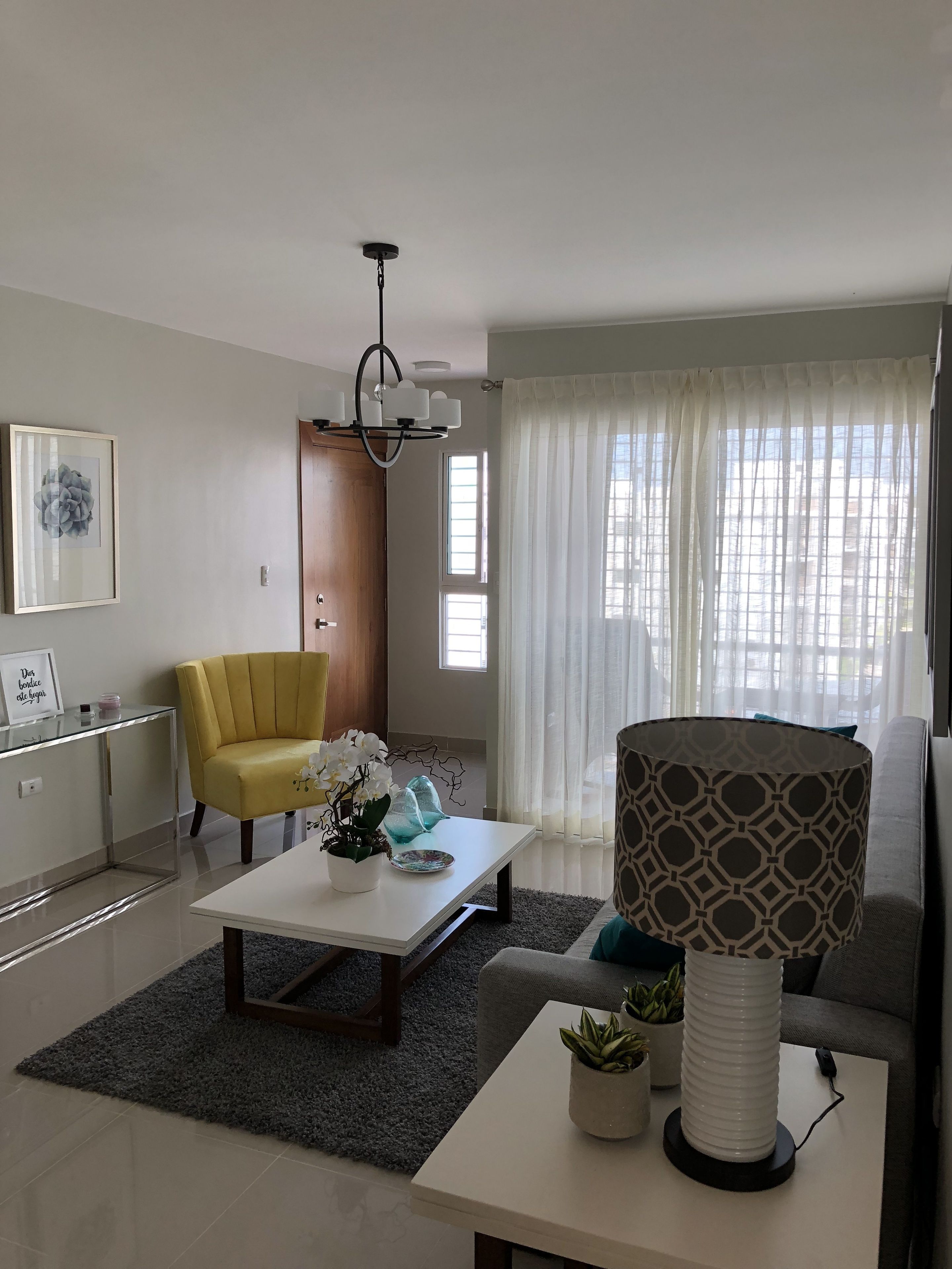 Un salon moderne avec un canapé, un fauteuil jaune, une table basse et un téléviseur.