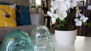 Two glass vases on a table, a potted orchid, and a patterned cushion on a sofa. - HeimatDorado R.D. your pleasant stay (Santiago de los Caballeros)