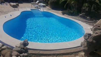 Una piscina al aire libre de temporada, sombrillas