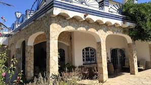 Un edificio in pietra con archi e tetto a tegole, dotato di posti a sedere all'aperto e un'area giardino.