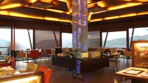 Un restaurant moderne doté d’un comptoir central, de grandes fenêtres et offrant une vue sur les montagnes.