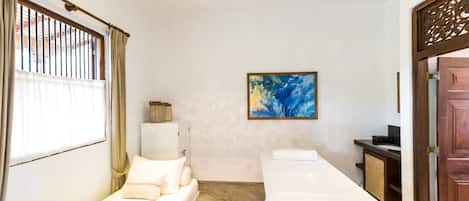 A room with two beds, a painting on the wall, and a wooden door.