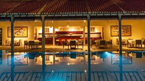 A hotel lobby with a swimming pool, dining area, and artwork on the walls.