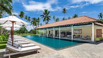 Una piscina al aire libre, sombrillas, sillones reclinables de piscina
