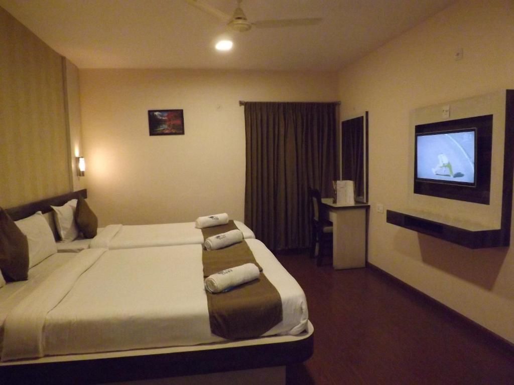 A hotel room with a bed, a desk, a television, and a ceiling fan.