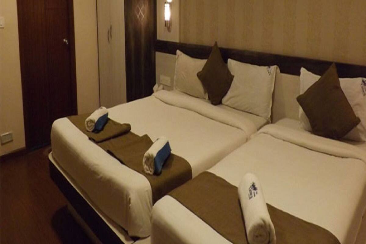 Una habitación de hotel con dos camas, un armario y una mesita de noche con lámpara.