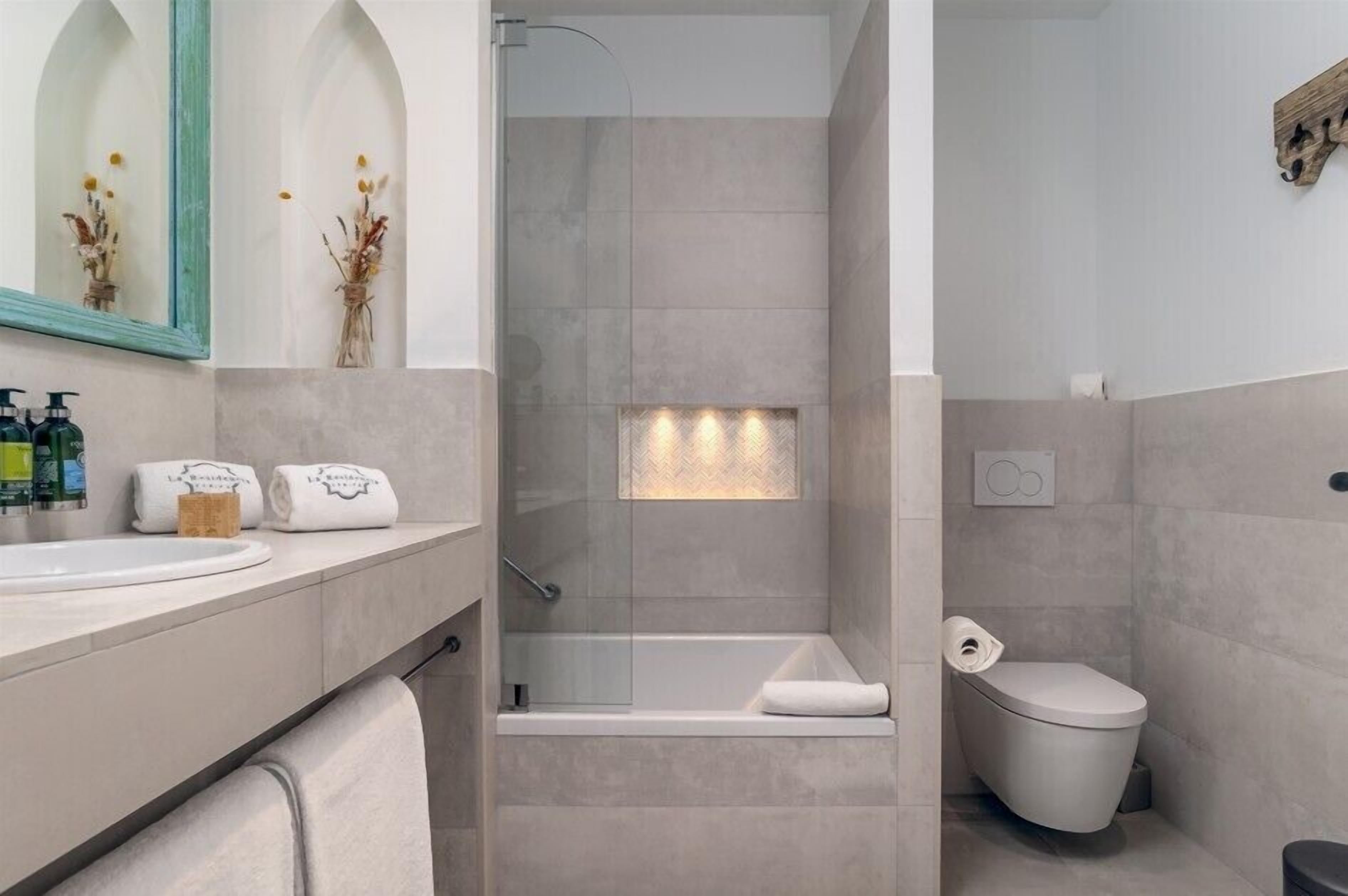 A modern bathroom with a shower, toilet, and sink.