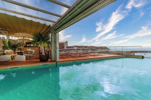 An indoor infinity pool with lounge chairs and a bar area.