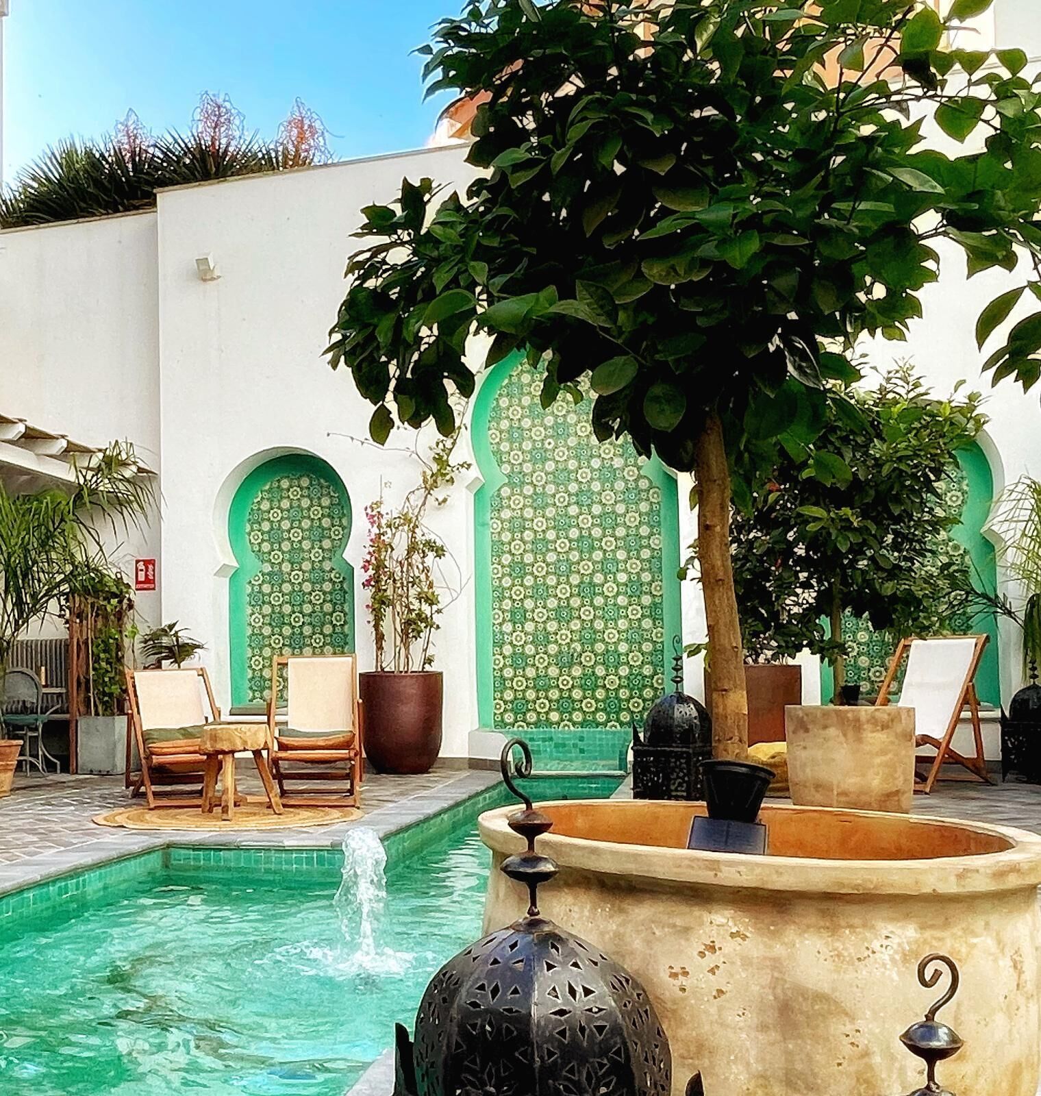 Un cortile con piscina, area salotto e fontane decorative.