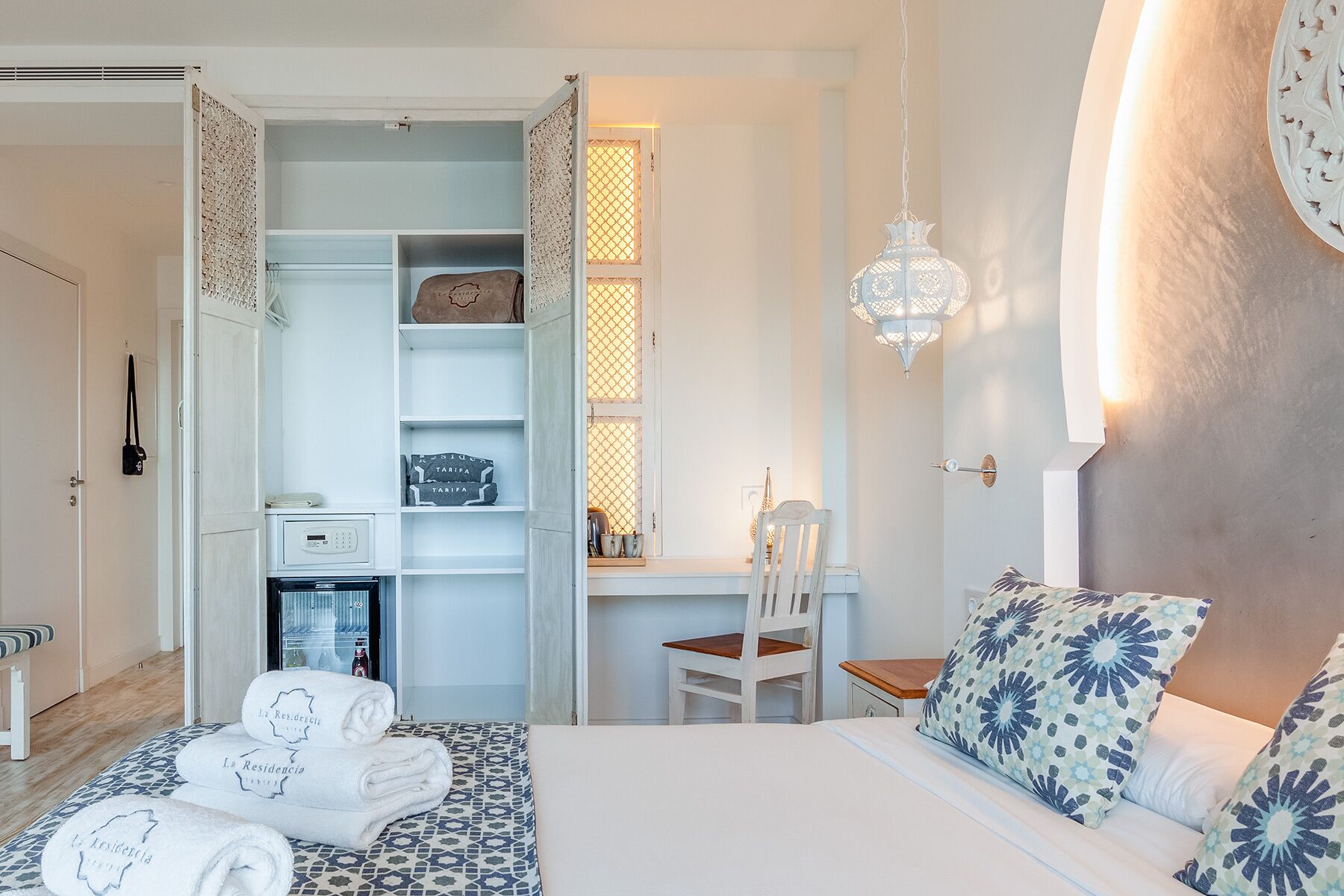Habitación de hotel con cama, escritorio, silla, armario y minibar.