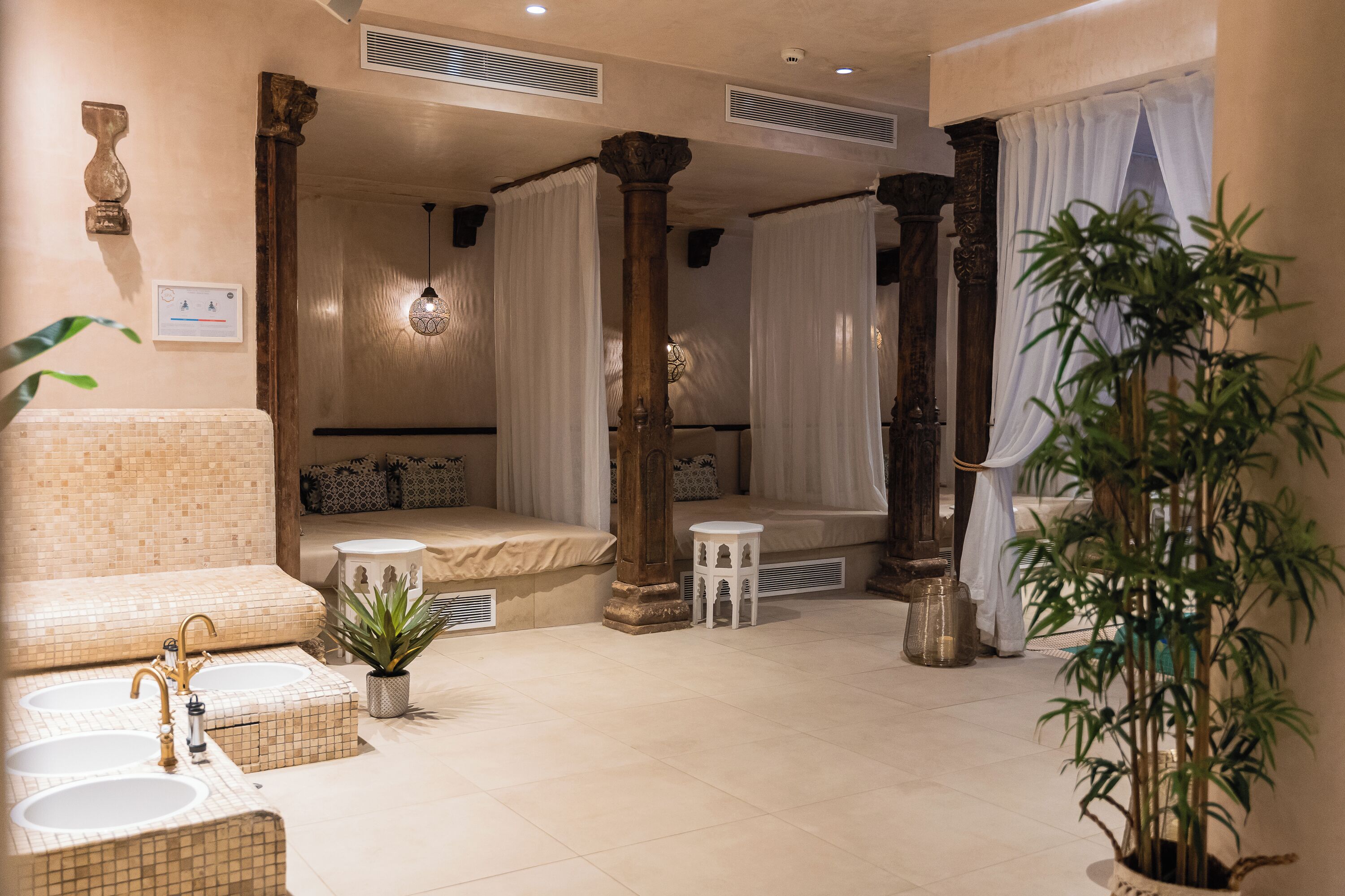 A spa-like room with a bathtub, a seating area with a bench, a small table, and a potted plant.