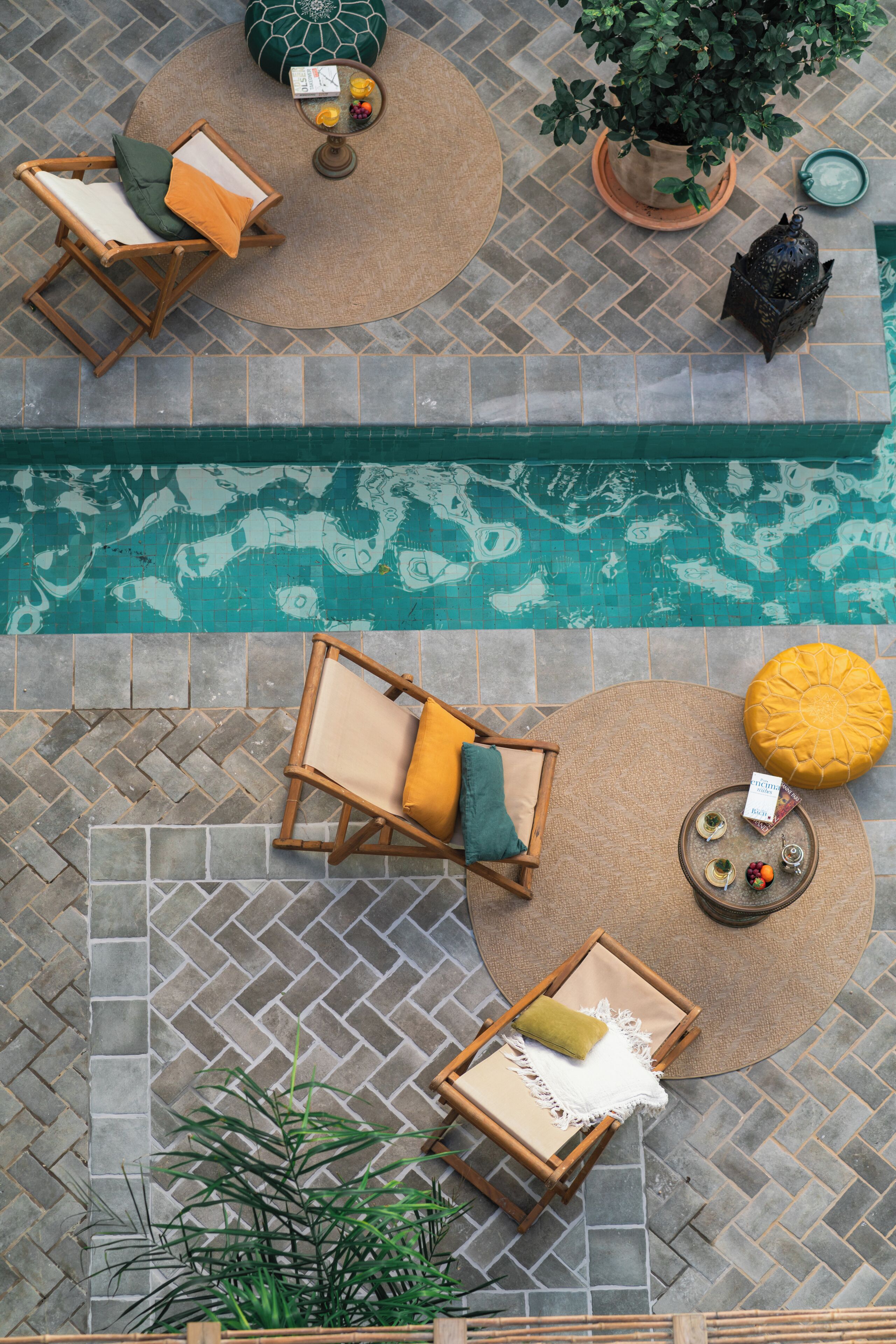 Un área de piscina en la azotea con sillones de descanso, una pequeña mesa con bebidas y plantas en macetas.