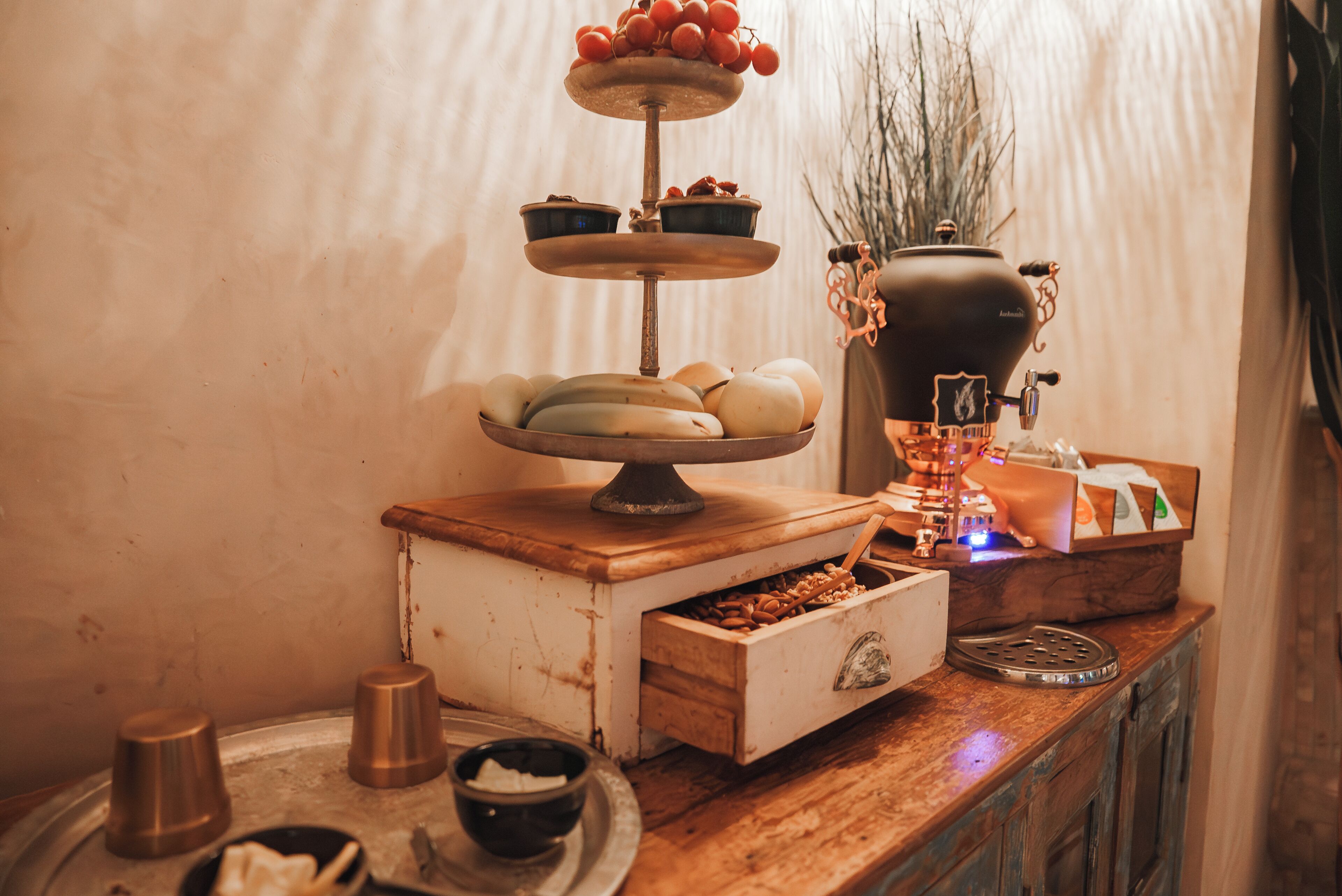 A buffet setup with a tiered serving tray, a wooden sideboard, and a decorative vase.