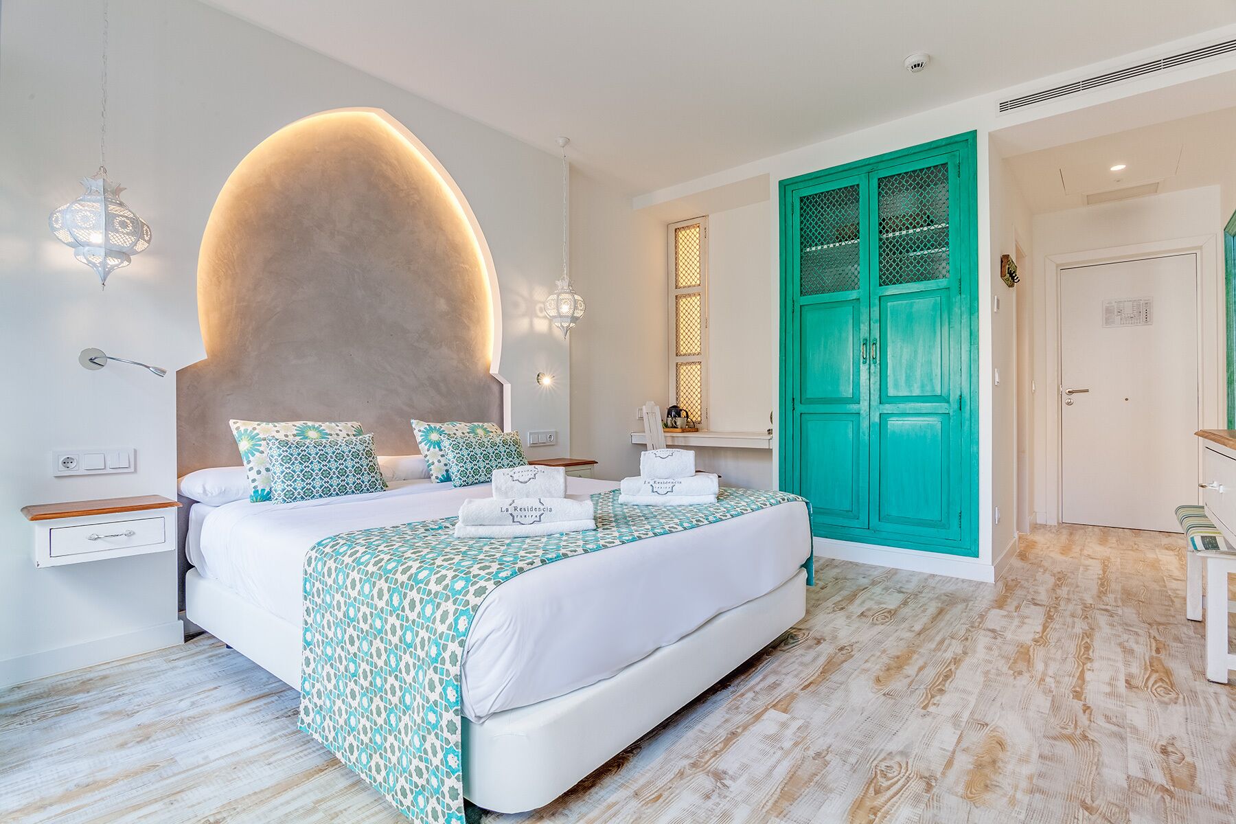 A modern bedroom with a large bed, a green door, and a unique wall feature.
