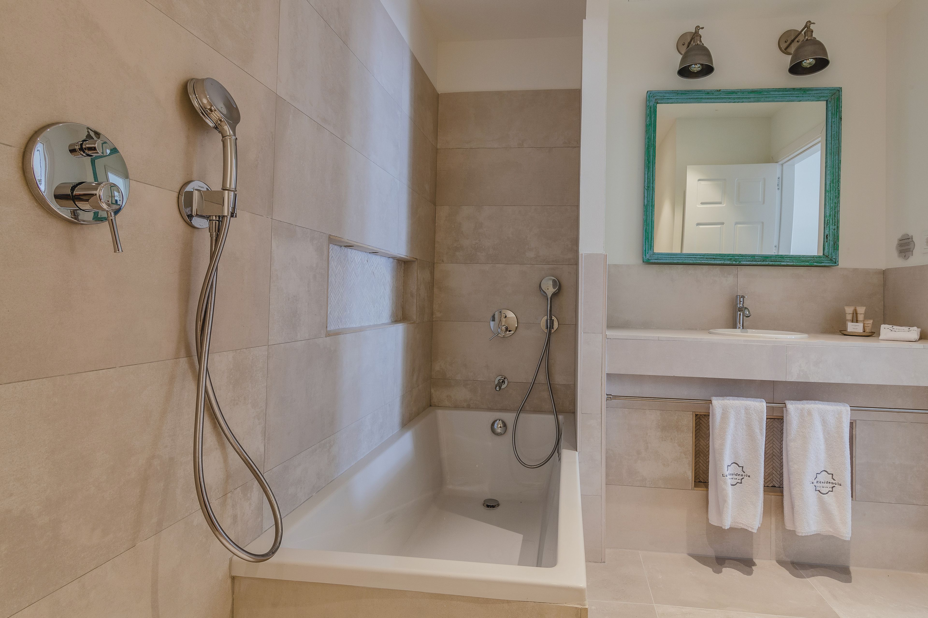 A modern bathroom with a bathtub, shower, and sink. There are towels hanging on the wall.