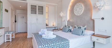 A modern bedroom with a large bed, bedside tables, a nightstand, a wall-mounted lamp, and a decorative wall piece.