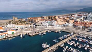 An aerial view of a coastal town with a marina, buildings, and a castle.