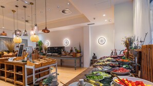 A restaurant with wooden furniture, hanging lights, and a variety of food displayed on the counter. - Hotel & Spa La Residencia Puerto (Tarifa)