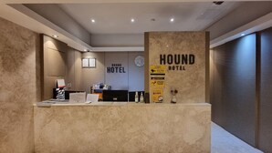 A reception desk at Hound Hotel with a modern design, a clock, and a sign indicating CCTV surveillance. - Hound Hotel Seomyeon - Bumcheon (Busan)