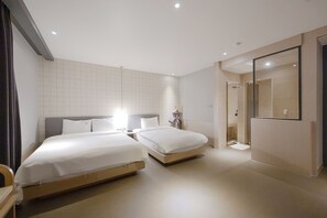 Ein modernes Hotelzimmer mit zwei Betten, einem großen Spiegel und einer begehbaren Dusche.