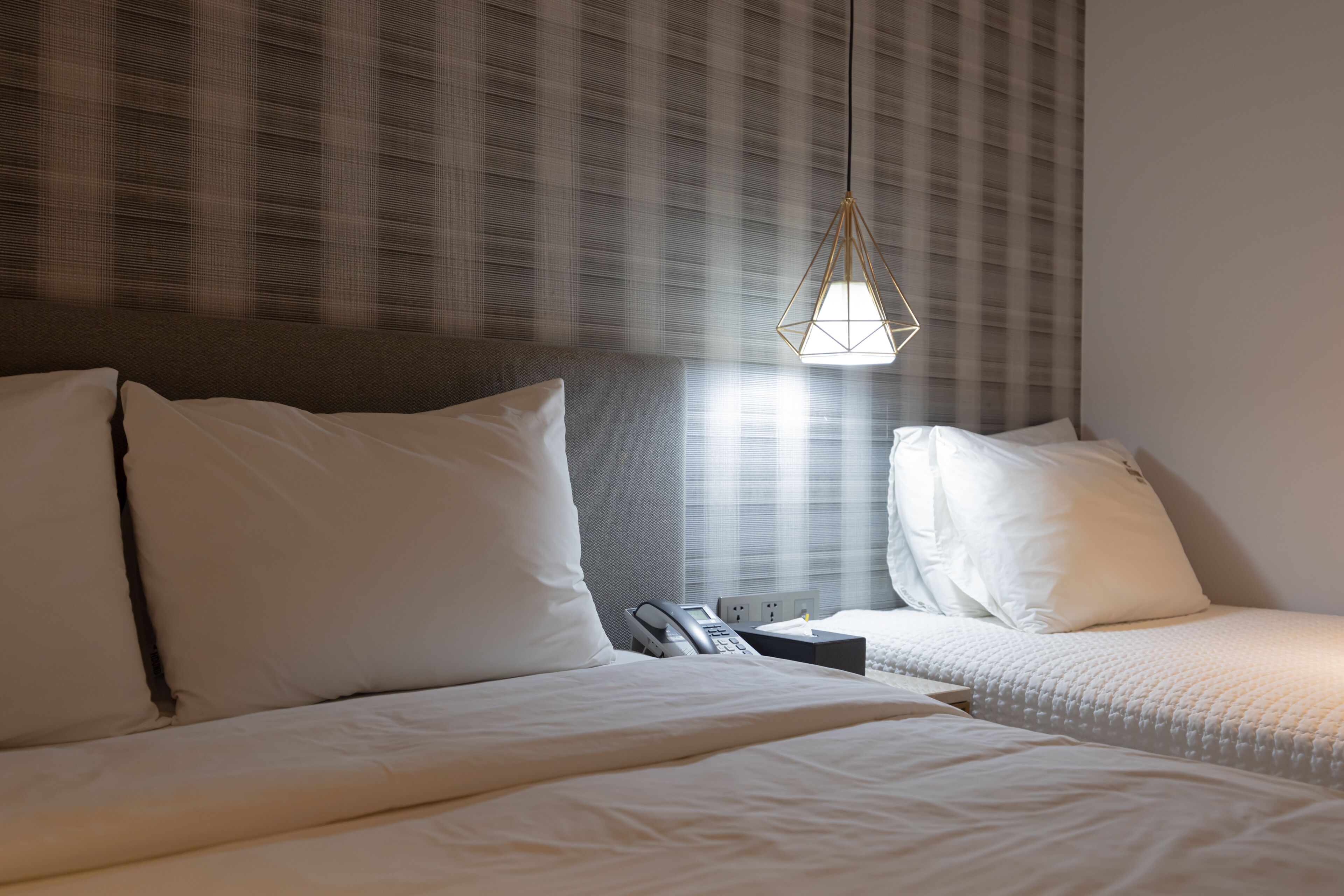 A hotel room with two beds, a telephone, and a nightstand.