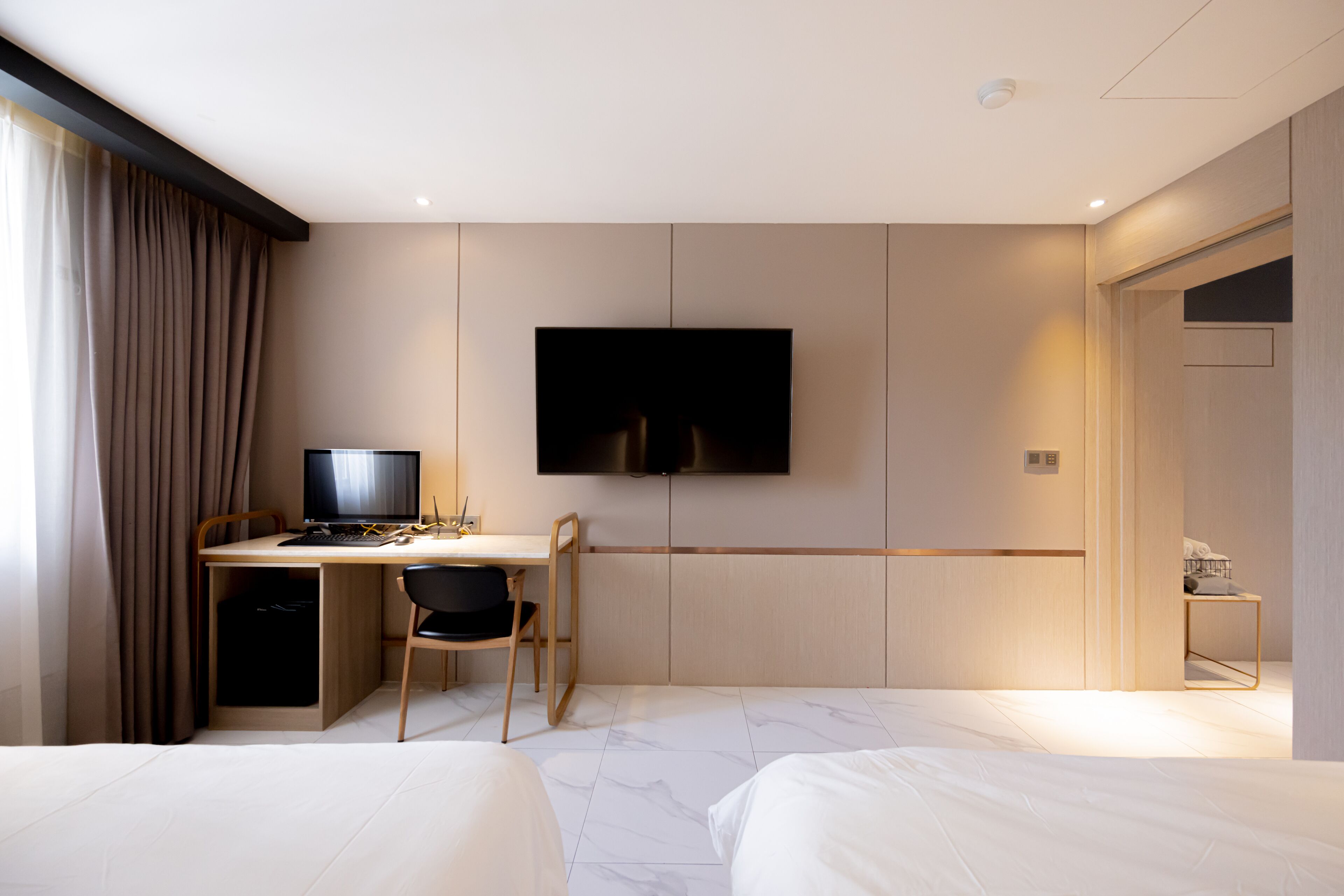 Una habitación de hotel con cama, escritorio con computadora, televisor y armario.