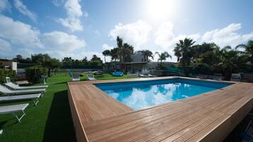 Una piscina al aire libre de temporada, tumbonas