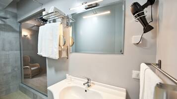 A modern bathroom with a large mirror, a white sink, and a hairdryer mounted on the wall.