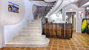 Un interior moderno con una escalera curva, un mostrador de recepción y una tabla de surf.