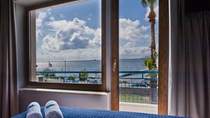 Habitación de hotel con una cama, vista al mar y un balcón con barandilla.