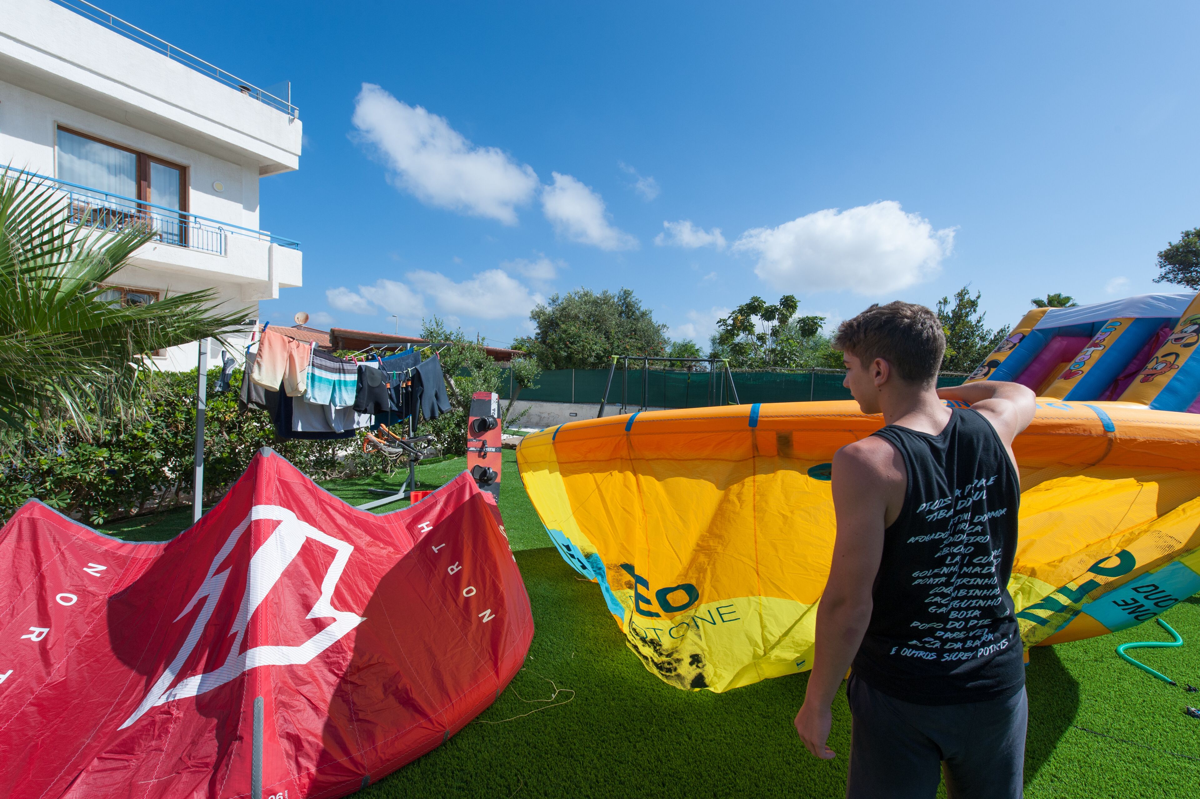 A person standing near colorful inflatable structures on a grassy area with a building in the background.