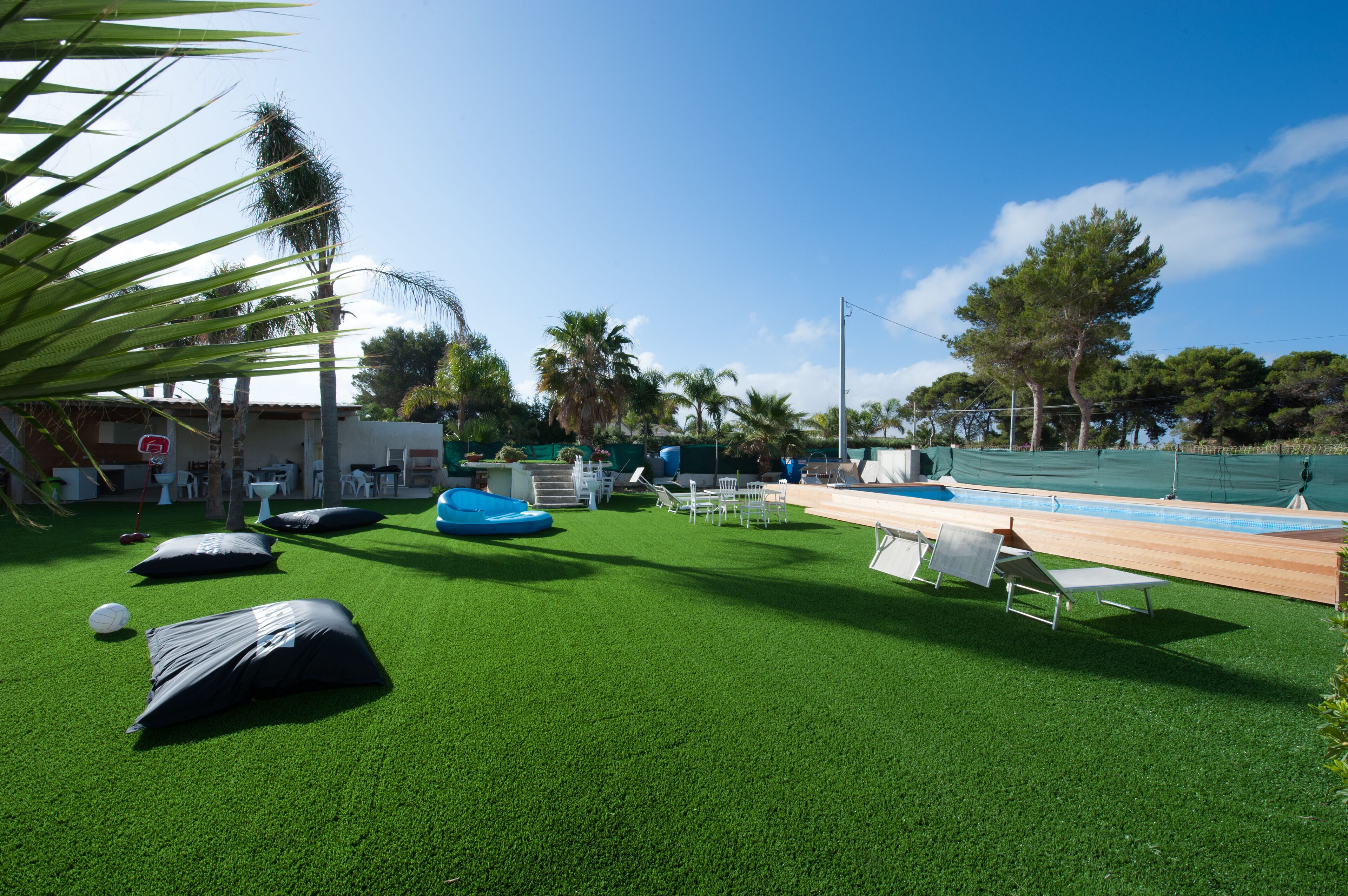 A pool area with artificial grass, lounge chairs, and a small pool.