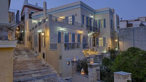 Un edifici de diverses plantes amb balcons, escales de pedra i il·luminació exterior.
