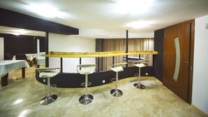 A room with a curved bar area, four bar stools, a long bar counter, and a door on the right. - Hotel Traveler (Kutaisi)