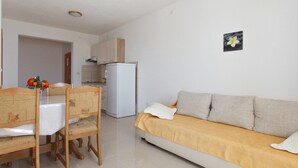 Un espacio habitable compacto con una mesa de comedor, sillas, un sofá, un refrigerador y una pequeña cocina.