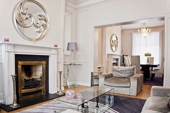 A spacious living room with a fireplace, a glass coffee table, and a comfortable seating area.