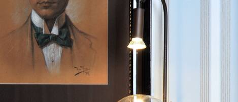 A framed portrait, a wall-mounted lamp, and a glass enclosure with a light.
