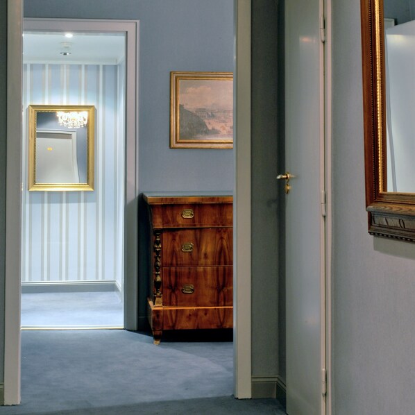 A hallway with a mirror, a framed picture, and a wooden cabinet.