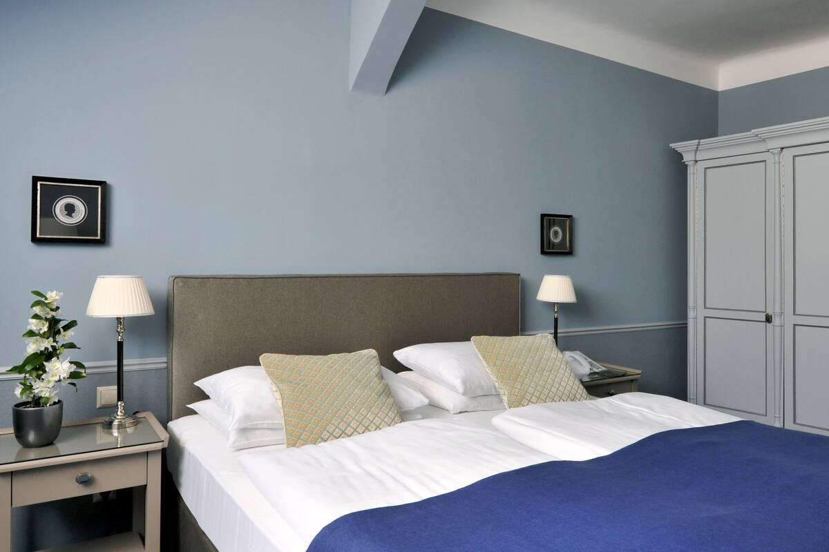 A neatly arranged bedroom with a bed, bedside tables, lamps, and a wardrobe.