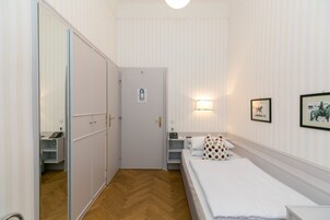Una camera d'albergo con un letto, un armadio, una scrivania e uno specchio.