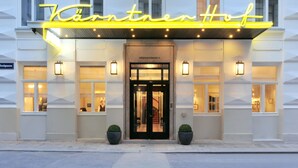 A hotel entrance with a neon sign, double doors, and two potted plants. - Hotel Kärntnerhof (Vienna)
