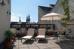 Una terraza en la azotea con sillones, una mesa y plantas en macetas.