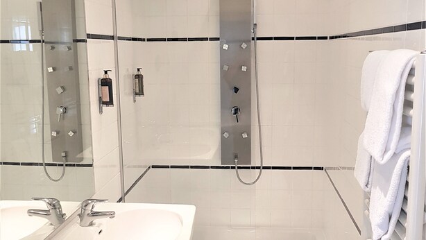 A modern bathroom with two sinks, a glass-enclosed shower, and a towel rack. - Hotel Kärntnerhof (Vienna)