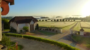 A rural landscape with a house, fields, and a clear sky.