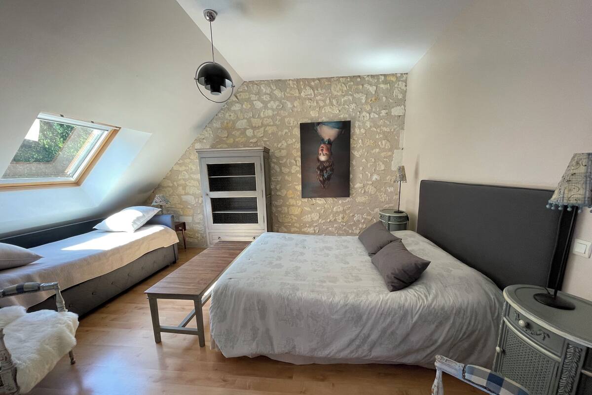 Ein Schlafzimmer mit Hochbett, Schreibtisch, Stuhl, Fenster und Steinwand.