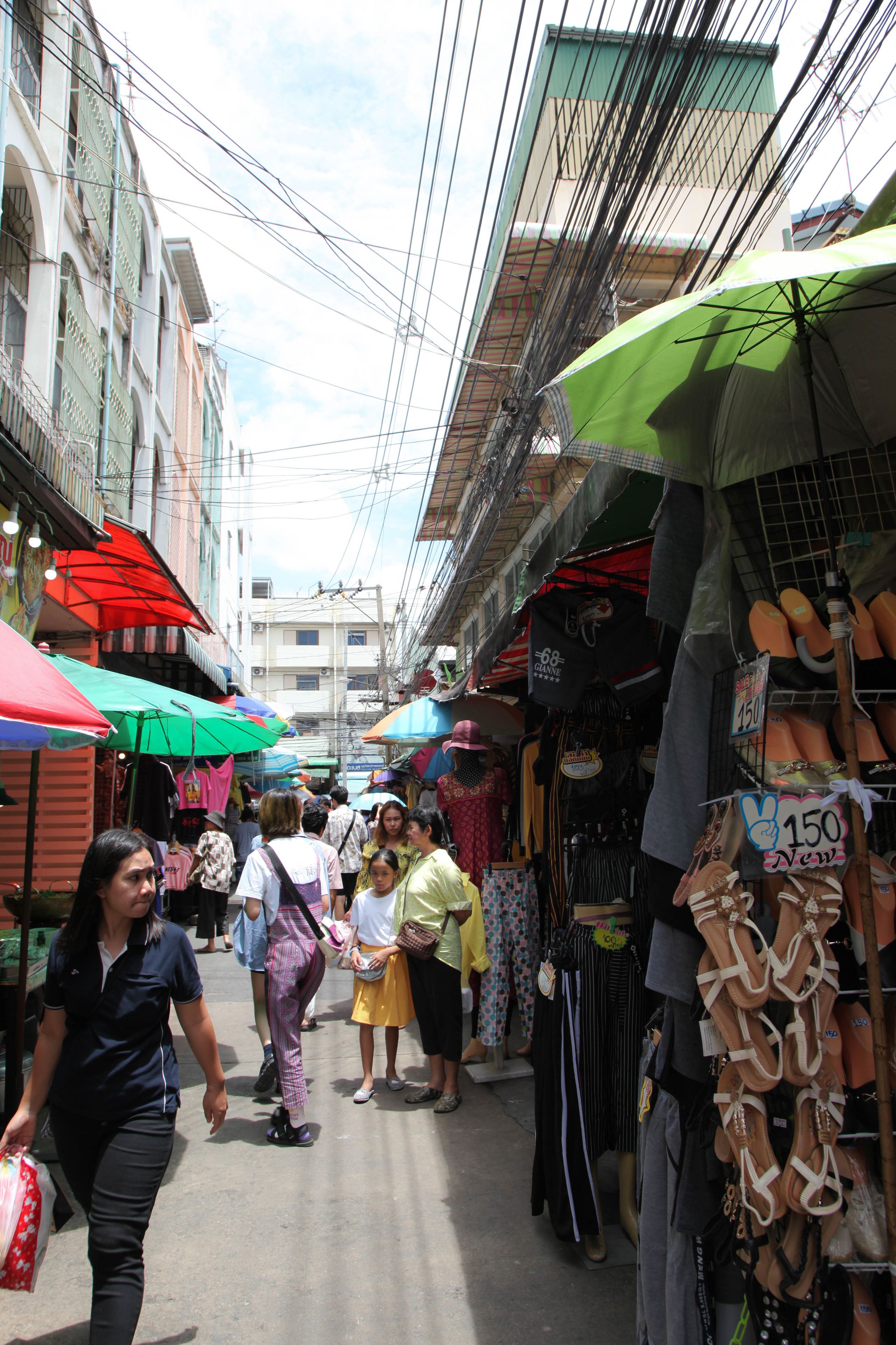 Une rue étroite bordée de boutiques et où l’on peut voir des vêtements suspendus.
